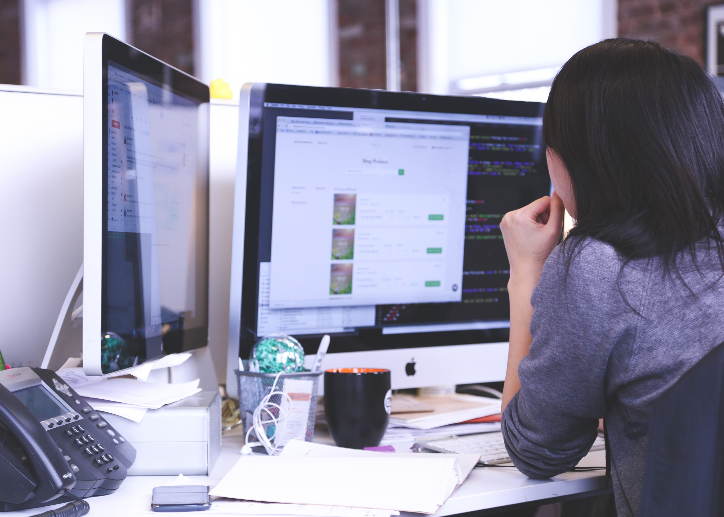 A woman at her computer workstation in an office setting.